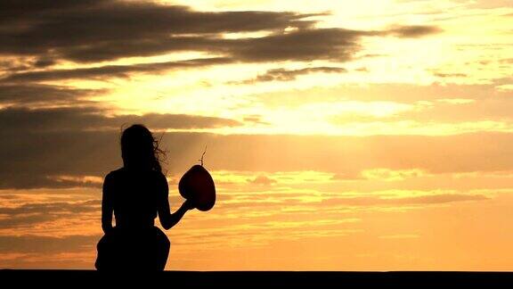 迷人的女孩拿着红气球欣赏日落