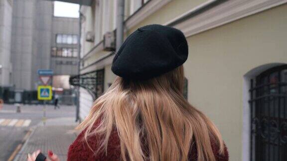 迷人的年轻女子在贝雷帽看着相机在城市的背景关闭了肖像拍摄