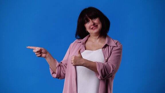 4k视频中一名女子在蓝色背景下微笑着竖起大拇指