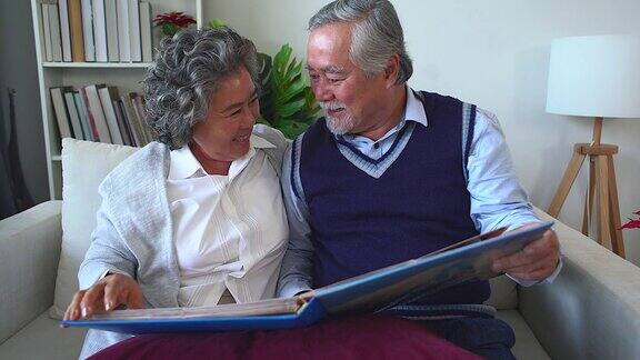 老夫妇打开相册回忆着快乐的时刻成年父母在相册里欣赏着回忆青春的照片退休夫妇花时间看旧相册