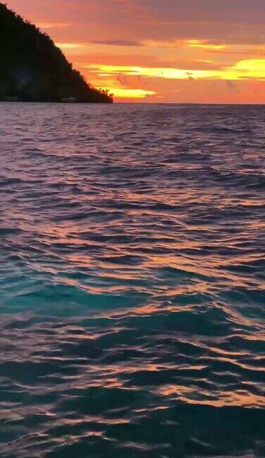 美丽的日落在海洋与野生热带岛屿在拉贾安帕水面与日出反射的垂直视频在巴布亚印度尼西亚