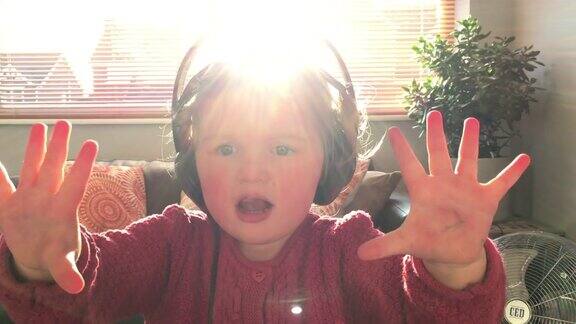小女孩戴着耳机在家听音乐