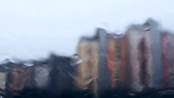 雨中的湿窗和背景中的城市