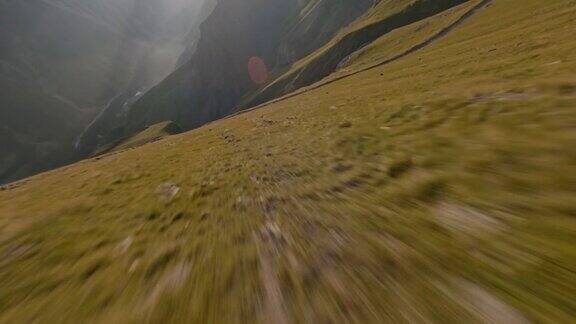 FPV无人机拍摄飞越阳光明媚的自然岩石山谷瀑布乡村路径石头地质