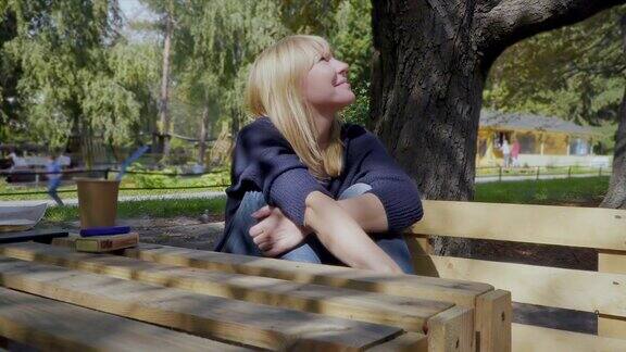 漂亮女人坐在公园的长椅上享受春天的天气
