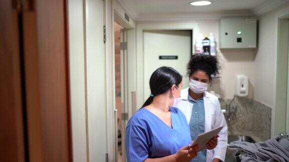 医疗工作者在医院戴着口罩行走和使用数字平板电脑