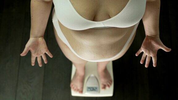 胖女人站在秤上拼命打手势胖肚子俯视图