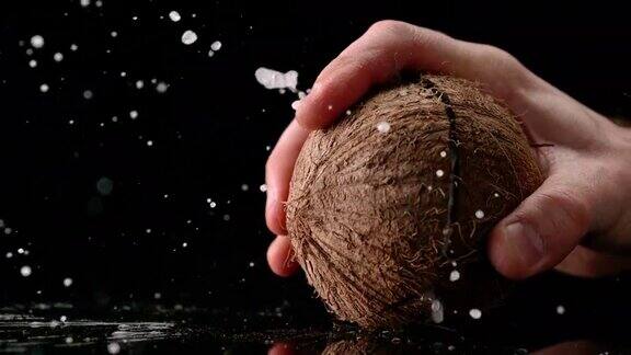 SLOMOLD手在表面上打碎一个椰子椰子裂开了