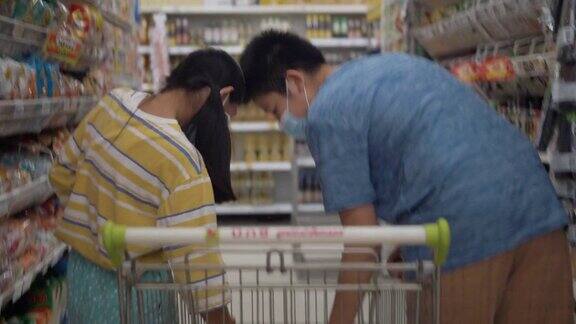 一名亚洲男孩和他的妹妹在封锁前戴口罩并为家人囤积食物生活方式概念