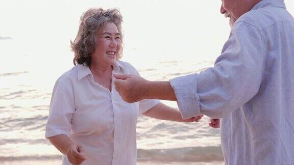 亚洲高年级情侣在沙滩上跳舞一起笑有生活方式、情感和退休观念的人慢动作镜头