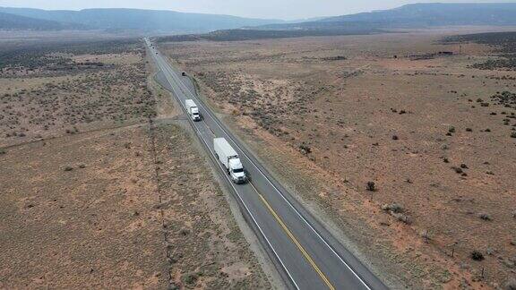 无人机观察半卡车在摩押附近的犹他州西南部红岩砂岩地区沙漠四车道高速公路上超速行驶