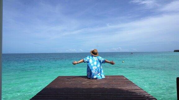 女人放松在明亮的蓝色夏季海洋享受4k假期的海风