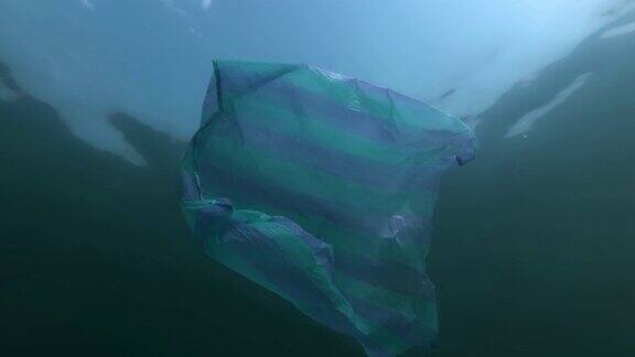 塑料污染条纹蓝袋在阳光下游泳水面上的背景蓝天与云彩低角在水下塑料碎片塑料垃圾环境污染问题