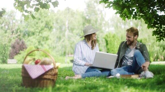 男男女女在野外用笔记本电脑野餐