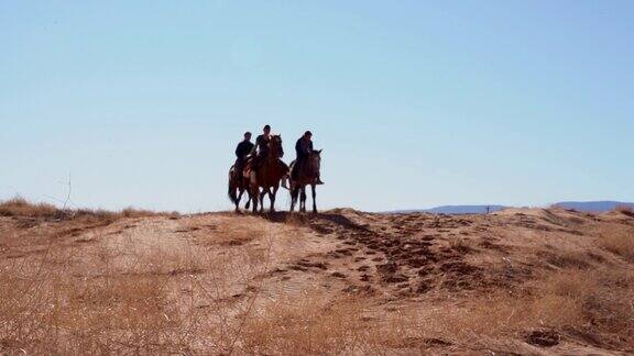 四个年轻的印第安纳瓦霍兄弟姐妹骑着他们的马在北亚利桑那纪念碑谷部落公园黄昏在一起