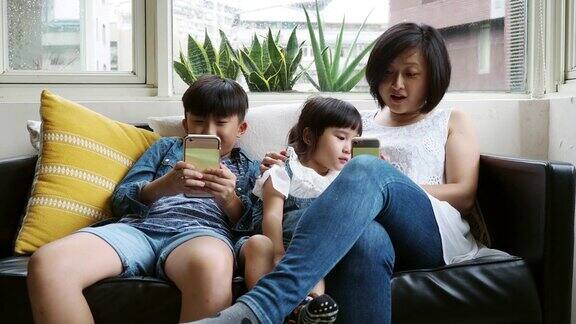 一家人一起用手机坐在家里的沙发上