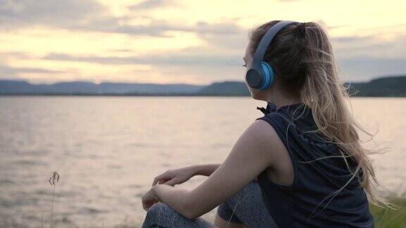 年轻女子在湖边听音乐的场景女子放松快乐时光