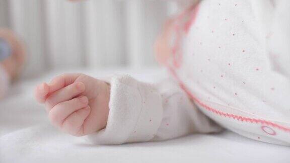 闭上宝宝可爱的小手穿着睡衣躺在舒适柔软的白色床上