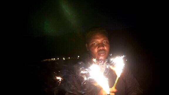 年轻的非洲男人在晚上手里拿着闪闪发光的东西