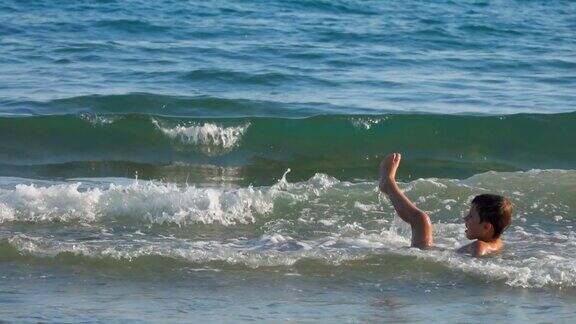 小男孩在溅起的海浪中玩耍