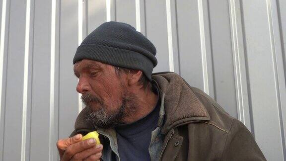 无家可归的人没有牙齿试图吃苹果