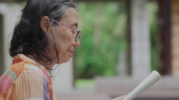 戴眼镜的老年妇女喜欢在户外读书