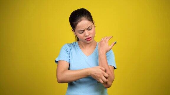 年轻女性有皮肤问题皮肤受到刺激皮肤感染发痒红疹子手臂用手抓痒隔离在黄色背景上