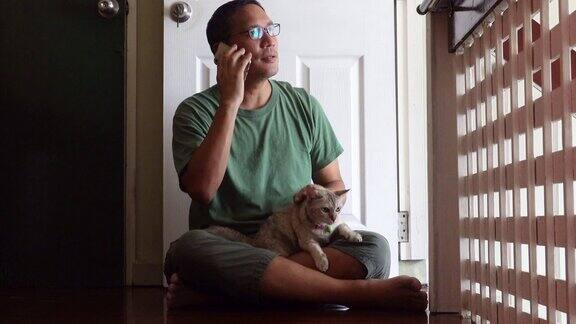 亚洲成熟男人坐在猫使用智能手机社交媒体或网上购物在家工作和网上商业概念