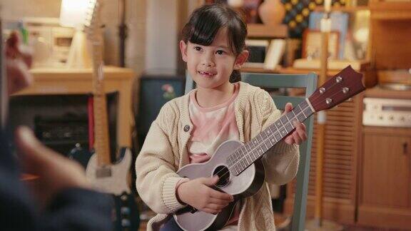 年轻的女孩正在学习弹尤克里里琴