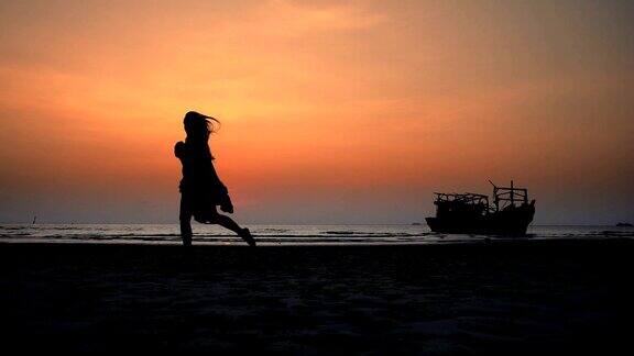 快乐的女孩穿着裙子在日落的海滩上跳