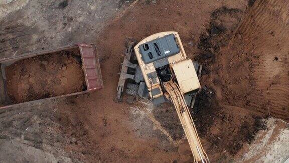 图为施工现场黄色液压挖掘机为房屋地基挖土并将土装上卡车俯视图