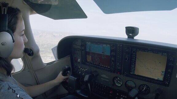 年轻的成年女性飞行员驾驶单引擎飞机切换待机和主动无线电频率