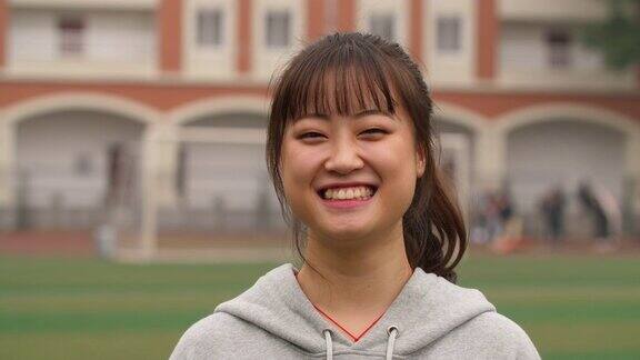 校园里年轻的亚洲女孩在镜头前微笑的肖像