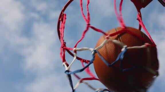 在户外街球场对着蓝天得分的篮球特写镜头