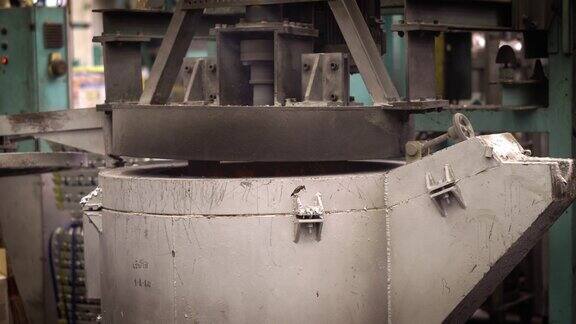 熔炼铝时操作者努力工作将熔化的金属从钢包上攻丝到保温炉压铸机上