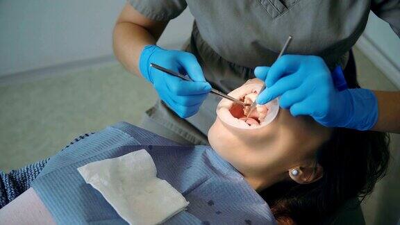 一位年轻女子在看牙医女性躺在牙科椅上医生在擦拭她的牙齿