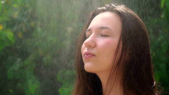 年轻美丽的女子在大自然的雨滴下