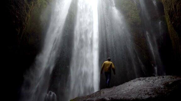 在大风天年轻男子站在冰岛强大的Gljufrabui瀑布附近的石头上