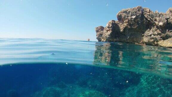 克罗地亚亚得里亚海一名身穿比基尼的年轻女子从岩石上跳入阳光灿烂的海洋