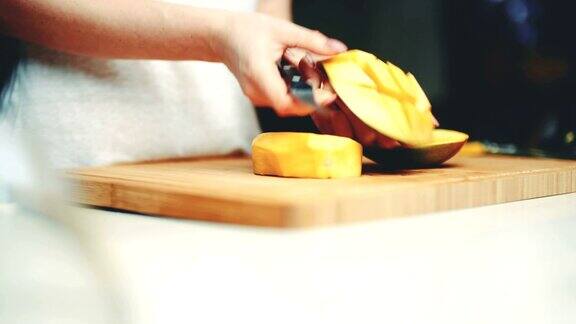 在切菜板上切芒果果肉的女人