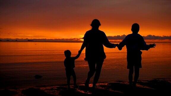 日落时分一家人手牵着手在海滩上奔向大海