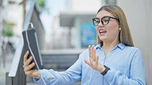 年轻的金发女商人微笑着自信地在街上进行视频通话