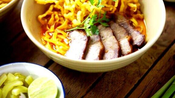 仰起镜头:KhaoSoi食谱木桌上放着泰国北部风味的咖喱面汤和猪肉