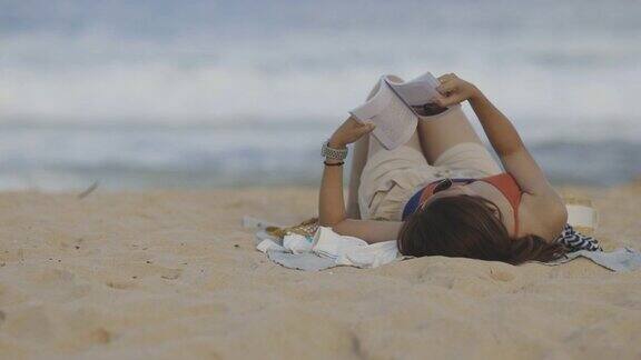 开朗的年轻女子在普吉岛海边的海滩上读书