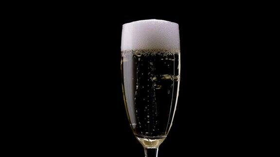 一杯里面有旋转气泡的香槟黑色背景近距离
