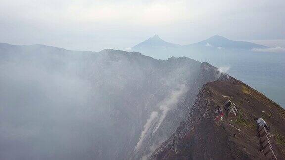 人们站在尼拉贡戈活火山的火山口边缘熔岩湖喷出浓烟