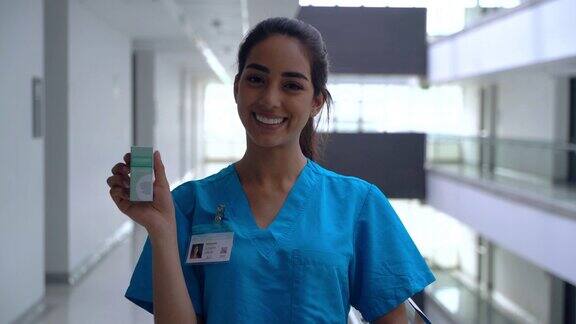 美丽的拉丁美洲护士拿着处方药而对着镜头微笑
