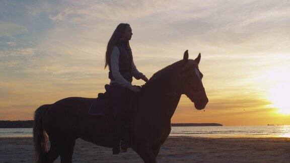 在日落光的海滩上的年轻骑手的剪影