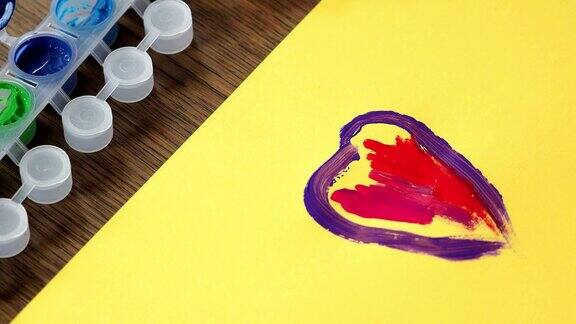 孩子正在画一幅画一个小女孩的手在黄色的纸上画了一个彩色的心
