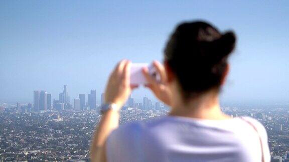 一个女人在拍摄洛杉矶市中心的照片4k慢镜头每秒60帧